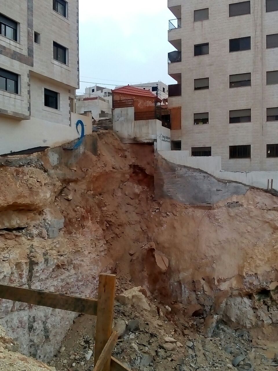 بالصور ..  حفرة إنشائية تهدد بانهيار عمارة سكنية بأكملها في القويسمة