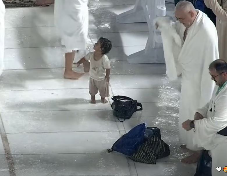 شاهد بالفيديو ..  طفل يخطف القلوب بفرحته تحت المطر في مكة المكرمة 