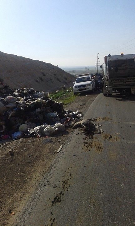 سائق قلاب نفايات يقوم بتفريغ حمولتة على الشارع الرئيسي في منطقة الاكيدر