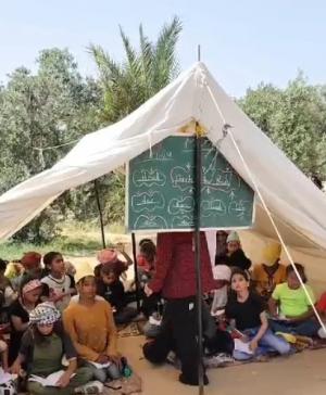 بالفيديو  ..  معلمة في غزة تقدم دروس اللغة الإنجليزية للأطفال داخل الخيام في ظل دمار مدارس القطاع