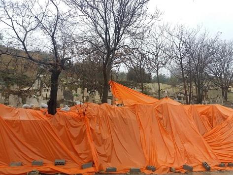 بالصور  .. تغطية قبور العيزرية بعد انهيار سور  ..   والاهالي لسرايا : تغطية القبور بـ"شادر" ليس كافيا 