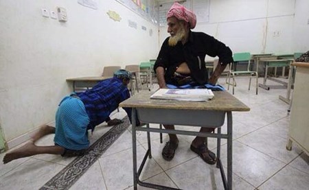 بالصور ..  خمسيني يُكافح إعاقته ويزحف لفصول محو الأمية لإكمال تعليمه 