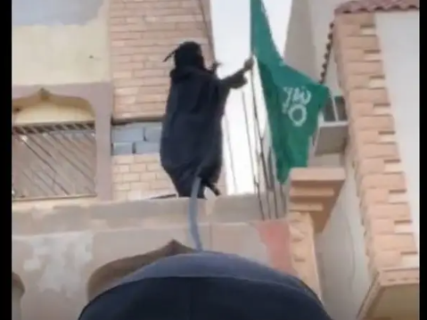 أشعلت منصات التواصل ..  مسنة تتسلق أسوار منزلها لترفع العلم السعودي - فيديو 