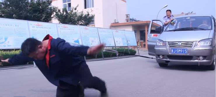 فيديو: صيني يسير بحذاء وزنه 300 كيلو جرام ويسحب سيارة برقبته!